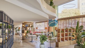 A modern interior with a curved ceiling, a central seating area, and a wooden bookshelf. - INNSiDE by Melia Barcelona Apolo (Barcelona)