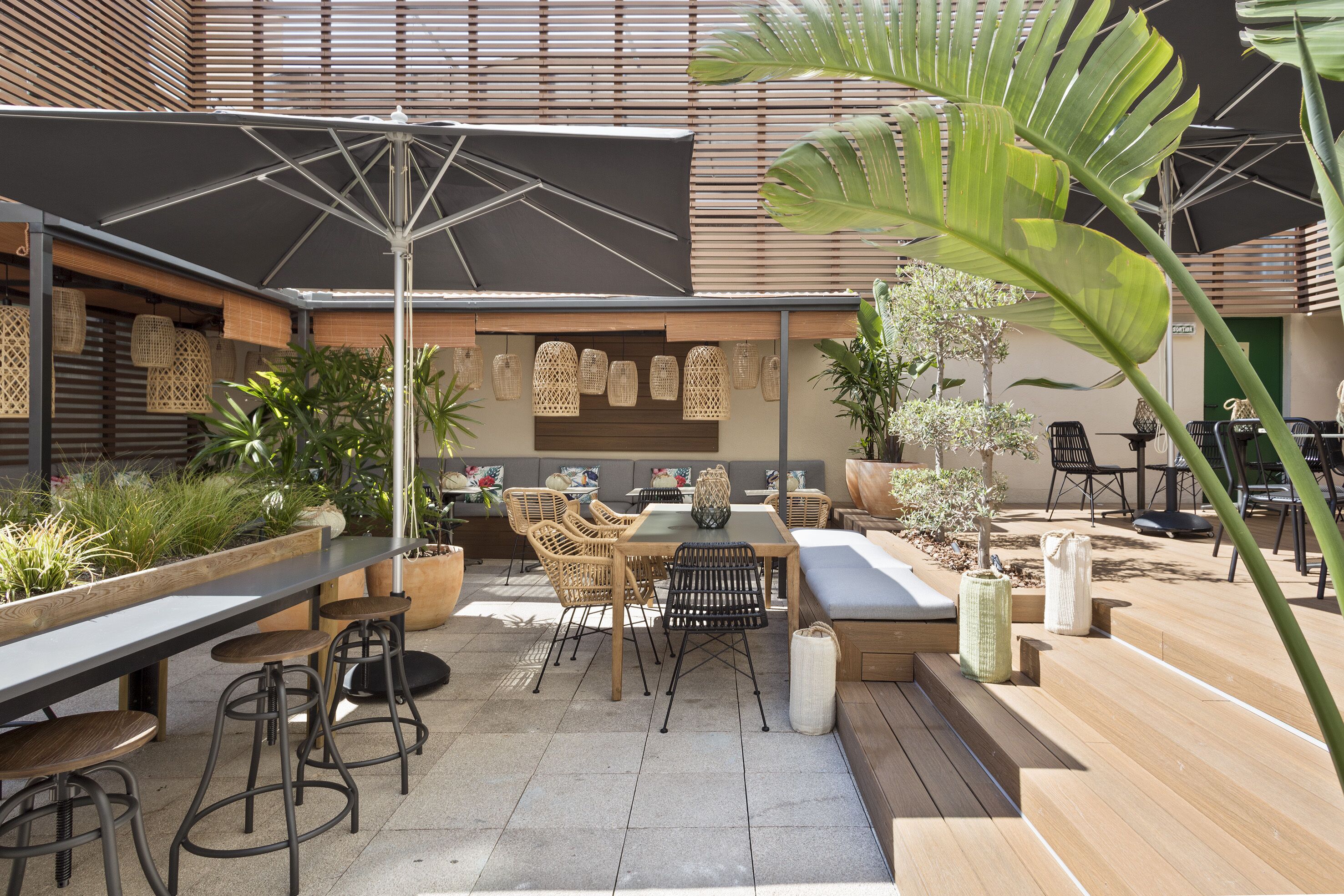 Une terrasse extérieure avec une table à manger, des chaises et un grand parasol.