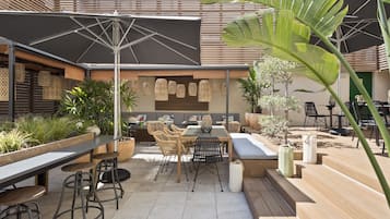 Une terrasse extérieure avec une table à manger, des chaises et un grand parasol.
