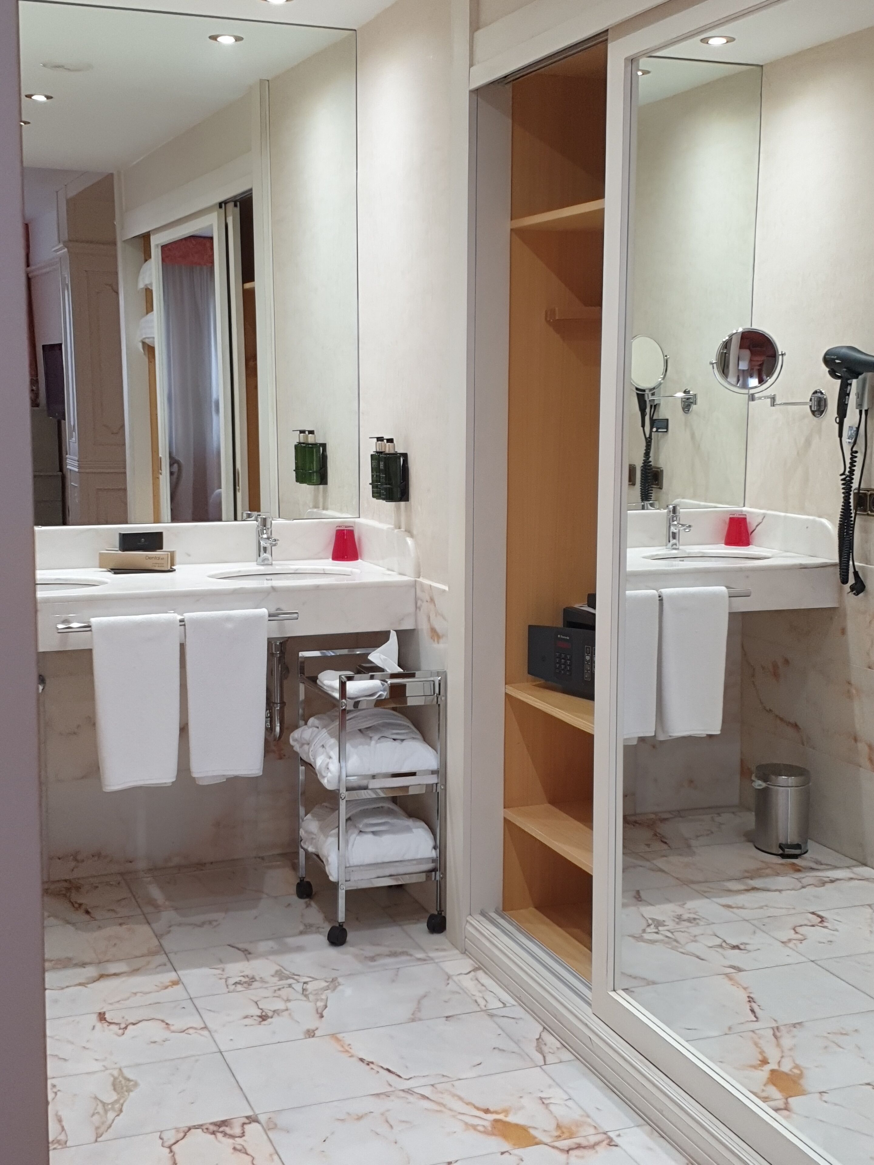 A modern bathroom with two sinks, a mirror, a hairdryer, and a towel rack.