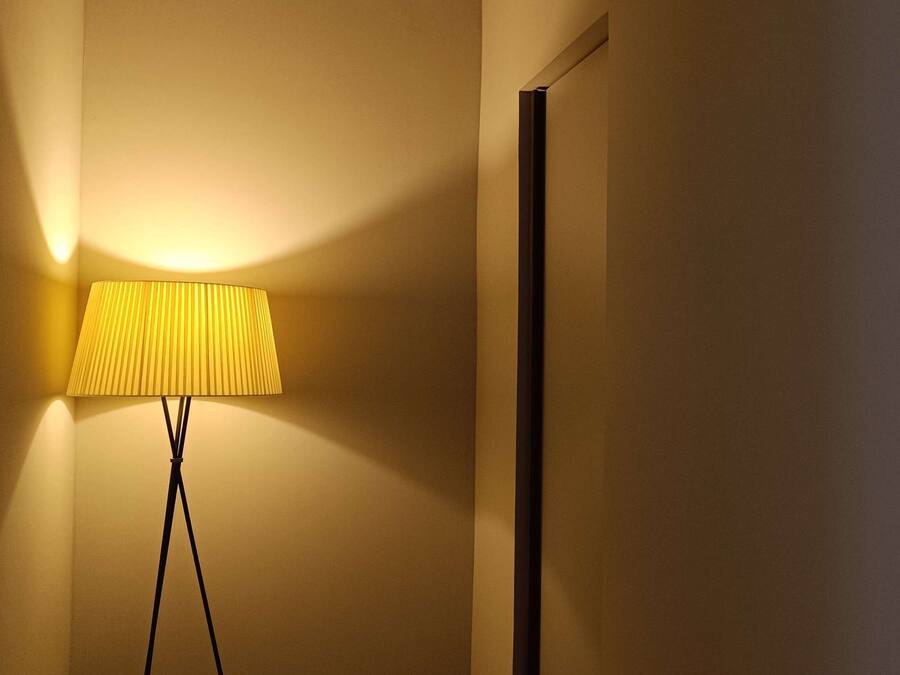 A lamp and a wall with a restroom sign.