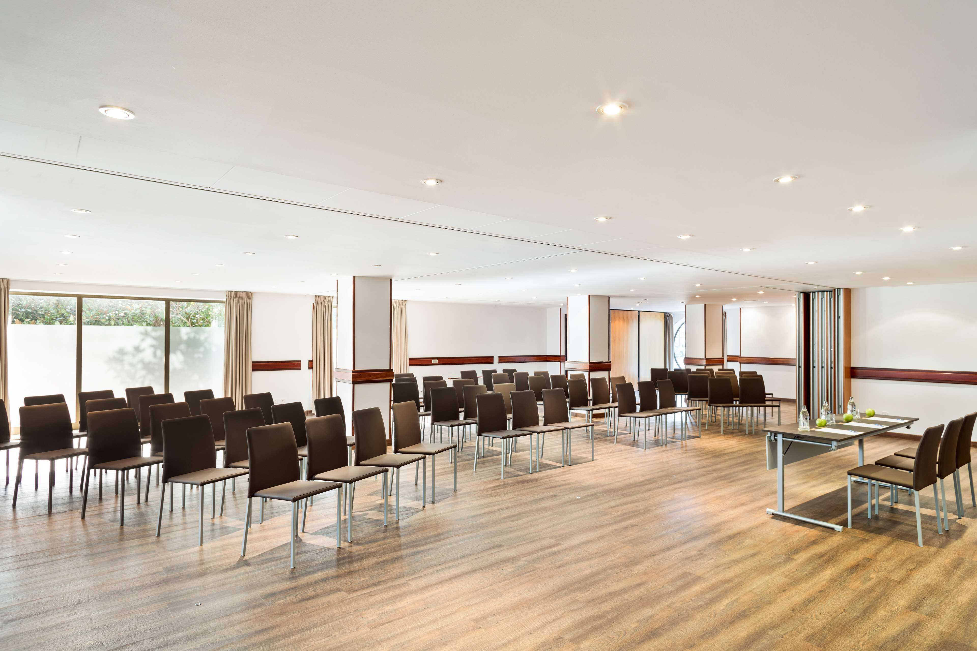 A conference room with rows of chairs, a long table, and a large window.