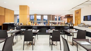 A modern hotel dining area with multiple tables and chairs, a central buffet, and a view of the cityscape. - Best Western Premier CMC Girona (Girona)