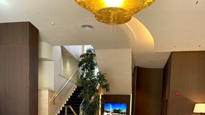 A modern living room with a curved sofa, two side tables, a potted plant, and a staircase leading to another level. - Best Western Premier CMC Girona (Girona)