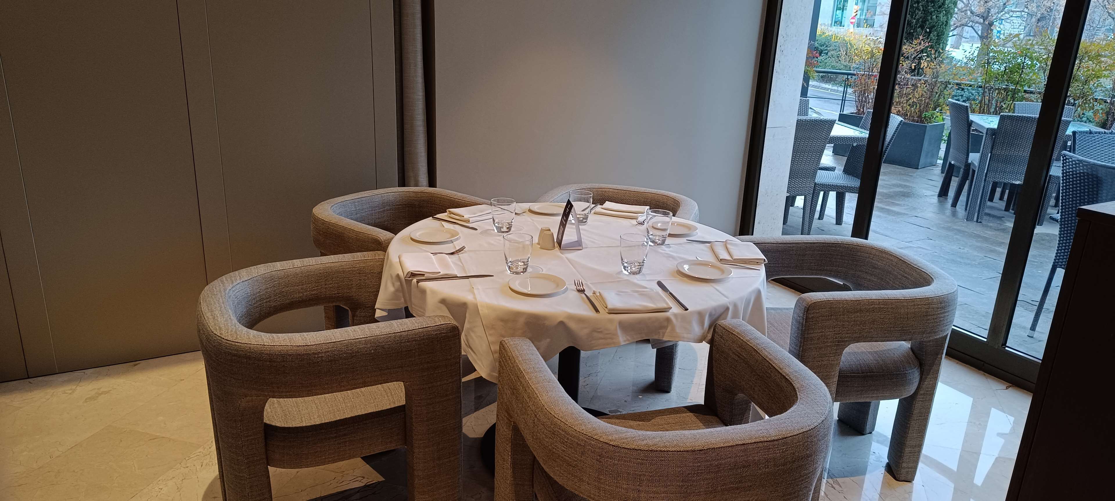 Een eetgedeelte met een ronde tafel voor vier personen, omringd door rieten stoelen.