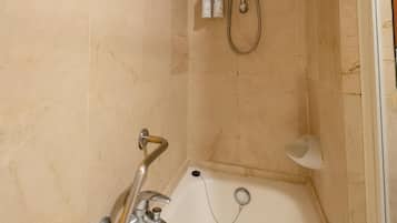 A bathroom with a bathtub, a shower, and two bottles of shampoo on the wall.