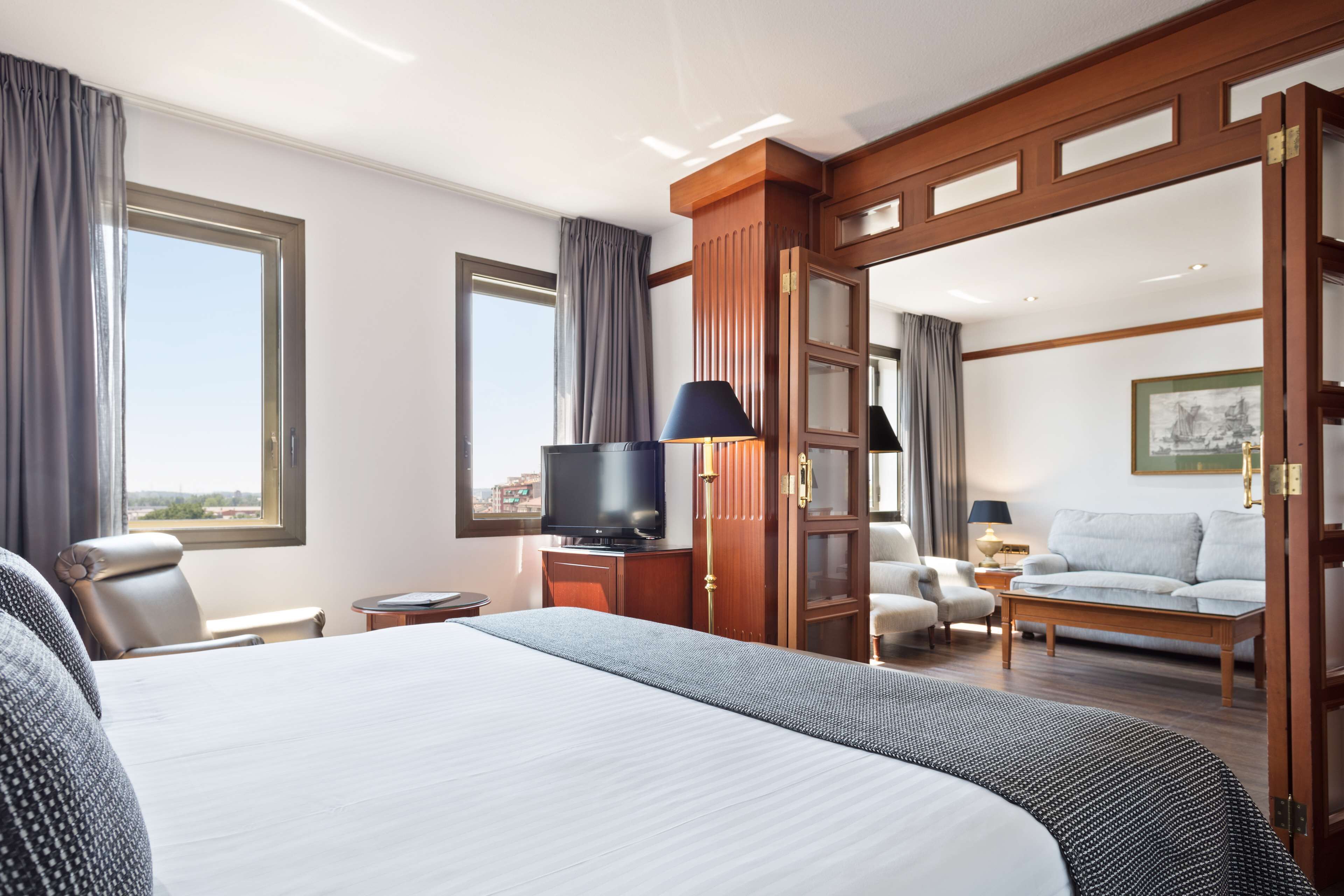 Een hotelkamer met een groot bed, een televisie, een sofa en een bureau.
