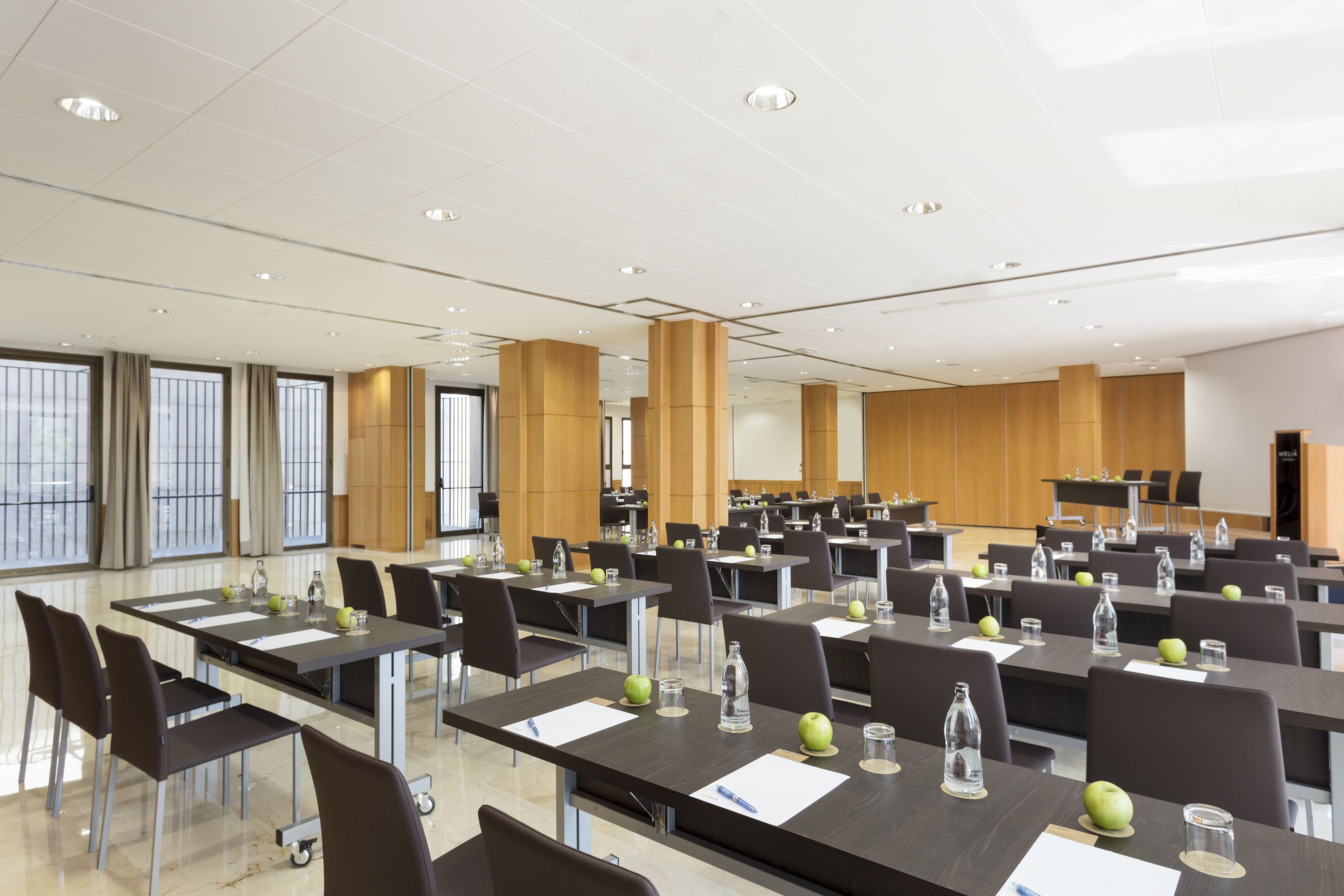 A conference room with multiple tables, chairs, and a large screen.