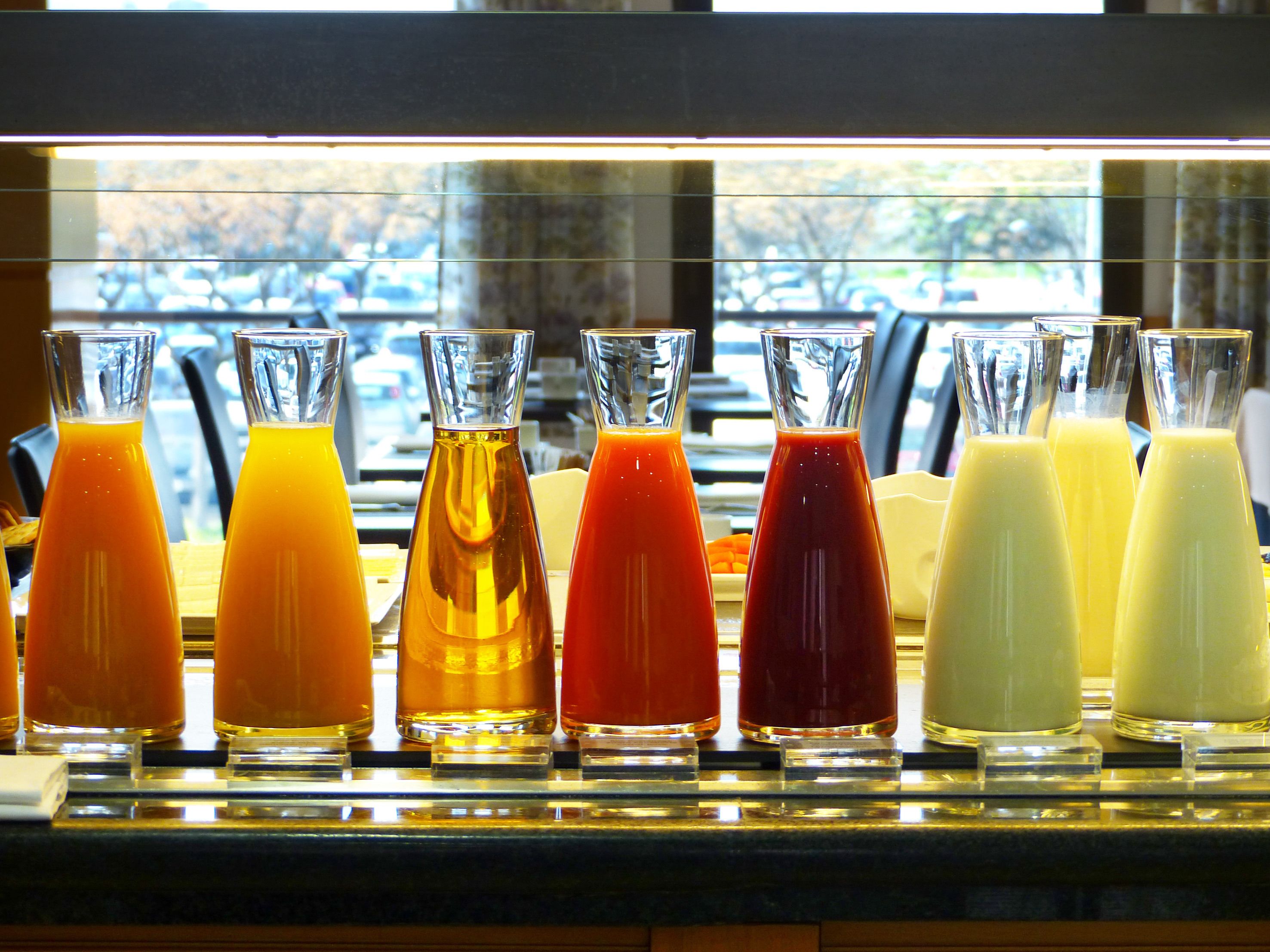 Varias bebidas de colores exhibidas en botellas de vidrio transparente.