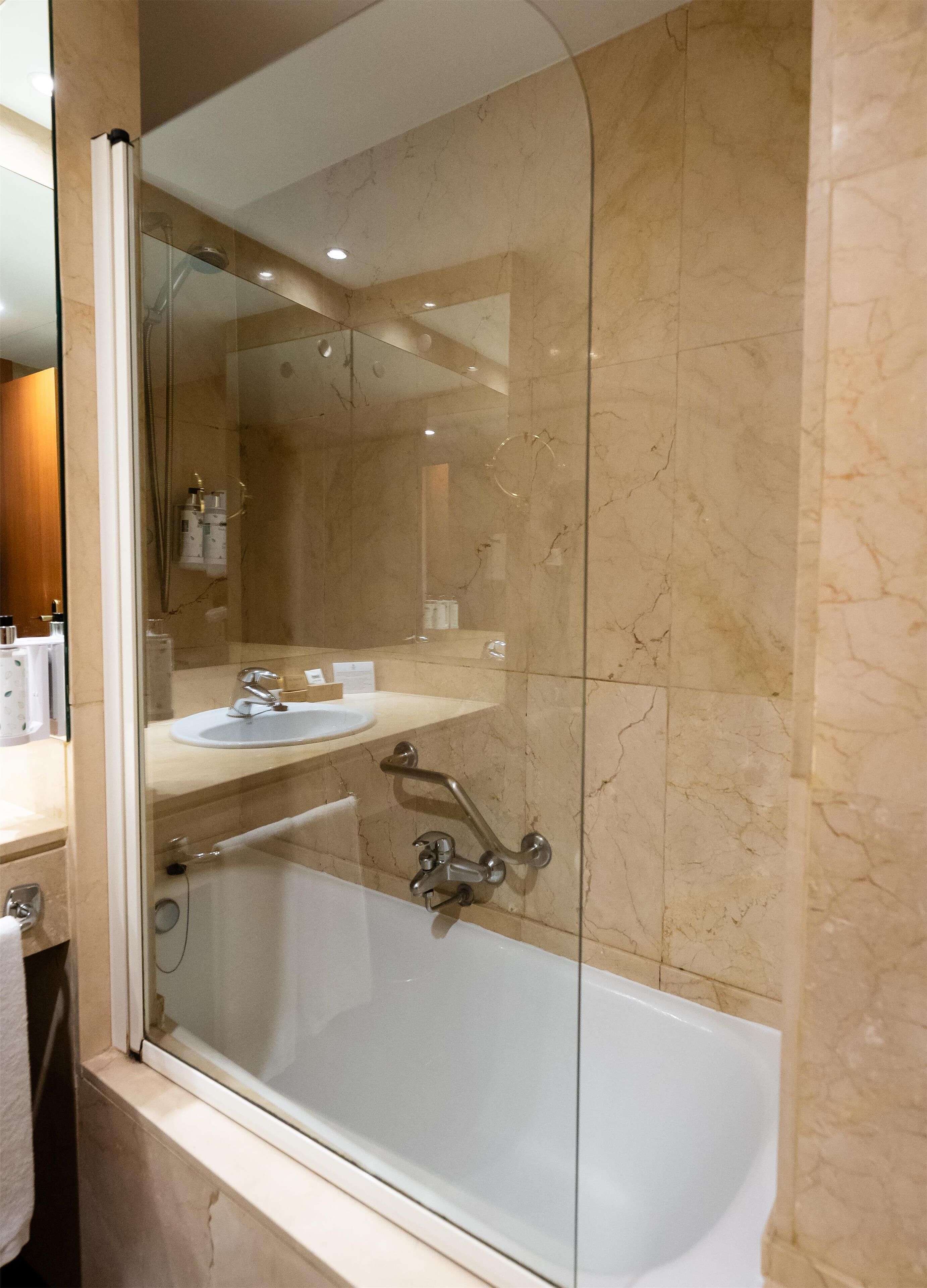 Un baño moderno con ducha de vidrio, una bañera blanca y un tocador con lavamanos.