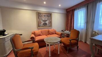 A hotel room with a sofa, two armchairs, a small round table, and a desk.