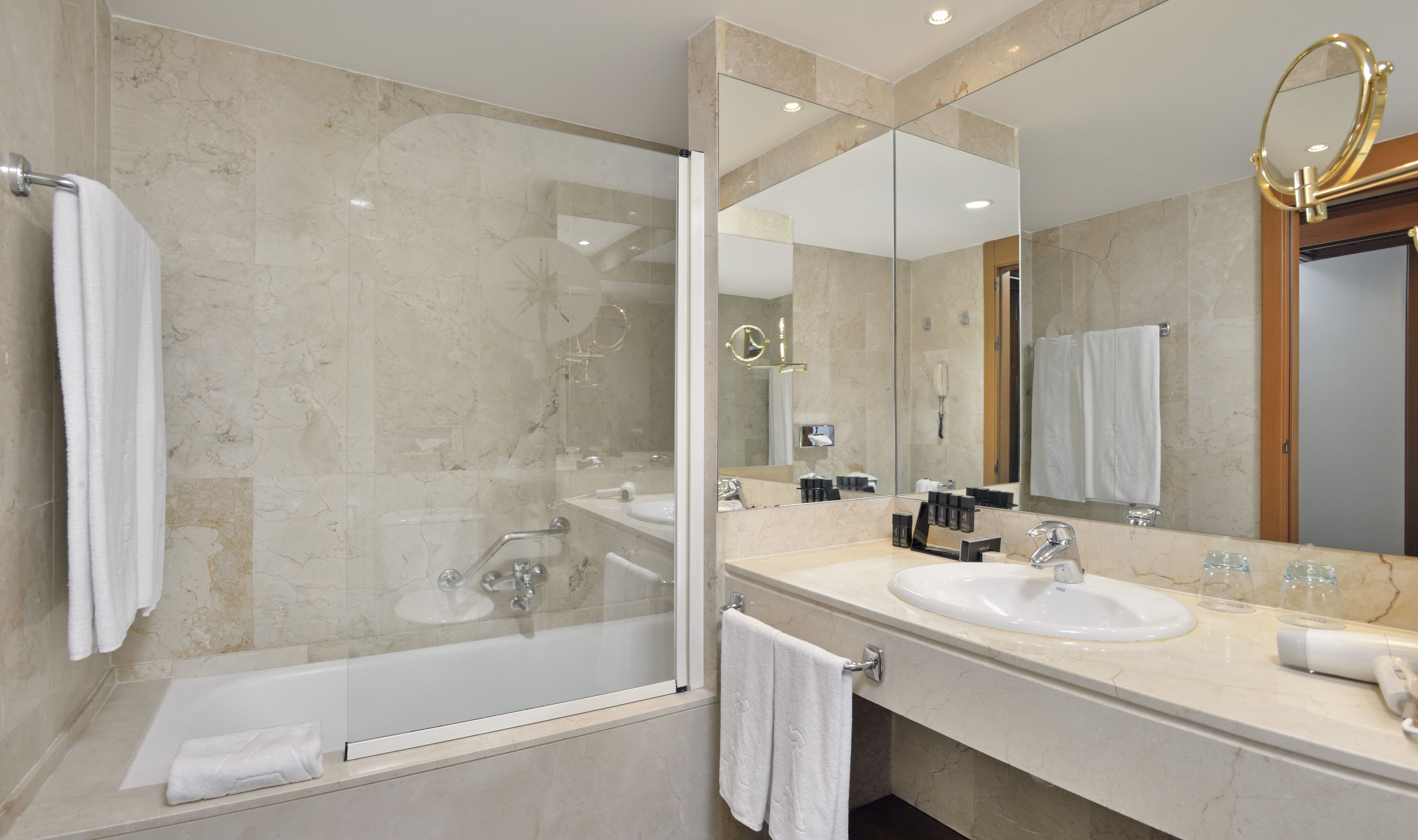 Une salle de bain moderne avec deux lavabos, une baignoire et un grand miroir.