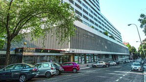 A modern high-rise building with a glass facade, surrounded by parked cars and trees. - Pierre & Vacances Apartamentos Edificio Eurobuilding 2 (Madrid)