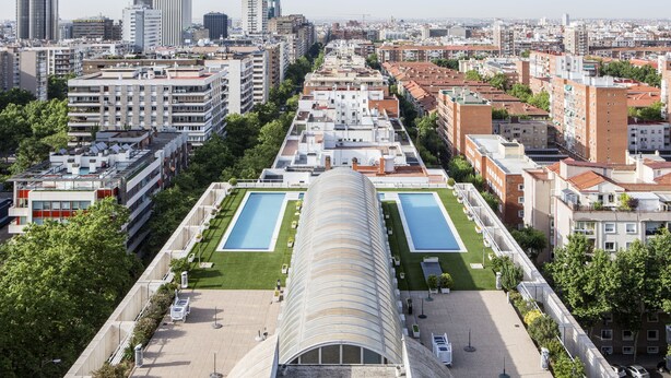 A modern hotel with a central swimming pool, surrounded by greenery and adjacent to a cityscape. - Pierre & Vacances Apartamentos Edificio Eurobuilding 2 (Madrid)
