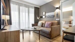 A modern living room with a wooden coffee table, a sofa, and a TV on a stand. - Pierre & Vacances Apartamentos Edificio Eurobuilding 2 (Madrid)