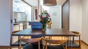 A modern dining area with a wooden table and chairs, a hanging light fixture, and a vase with flowers. - Pierre & Vacances Apartamentos Edificio Eurobuilding 2 (Madrid)