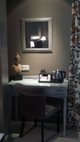 Una habitación pequeña y oscura con un escritorio, una silla, una lámpara y un objeto decorativo.