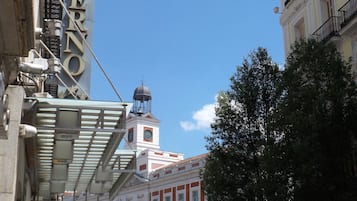 Un hôtel avec une enseigne bien visible, une tour horloge et une rue animée.
