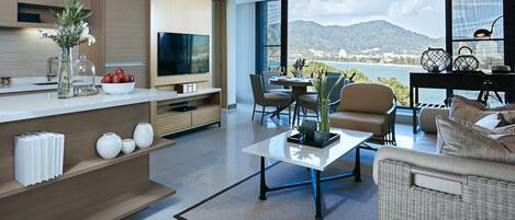 A modern living room with a large TV, dining area, and a view of the mountains.