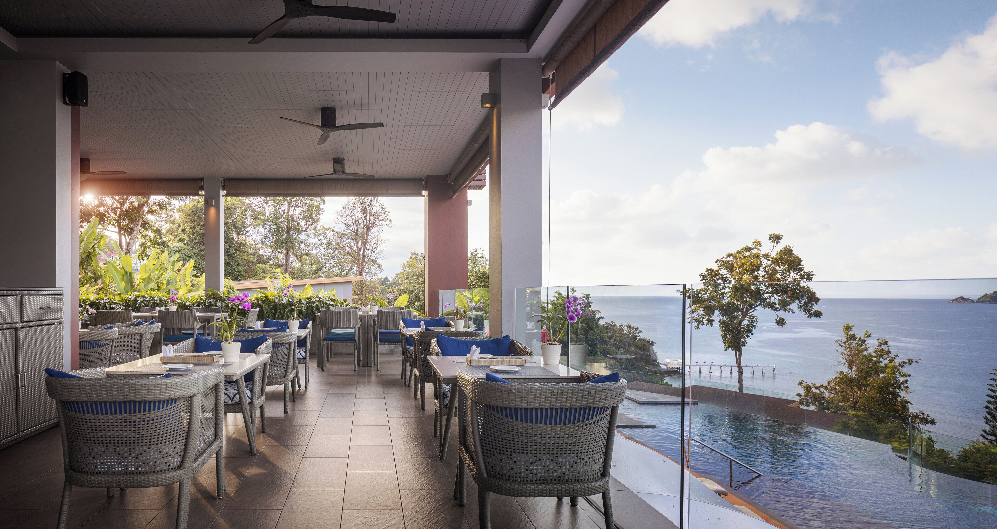 An outdoor patio with wicker furniture, a ceiling fan, and a view of the sea.