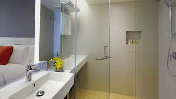 A modern bathroom with a glass-enclosed shower, a white sink, and a mirror.
