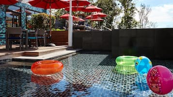 Relax by the pool surrounded by a low wall and shaded by umbrellas.