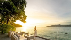 A serene outdoor seating area with a view of the sea at sunset. - Amari Phuket (Patong)