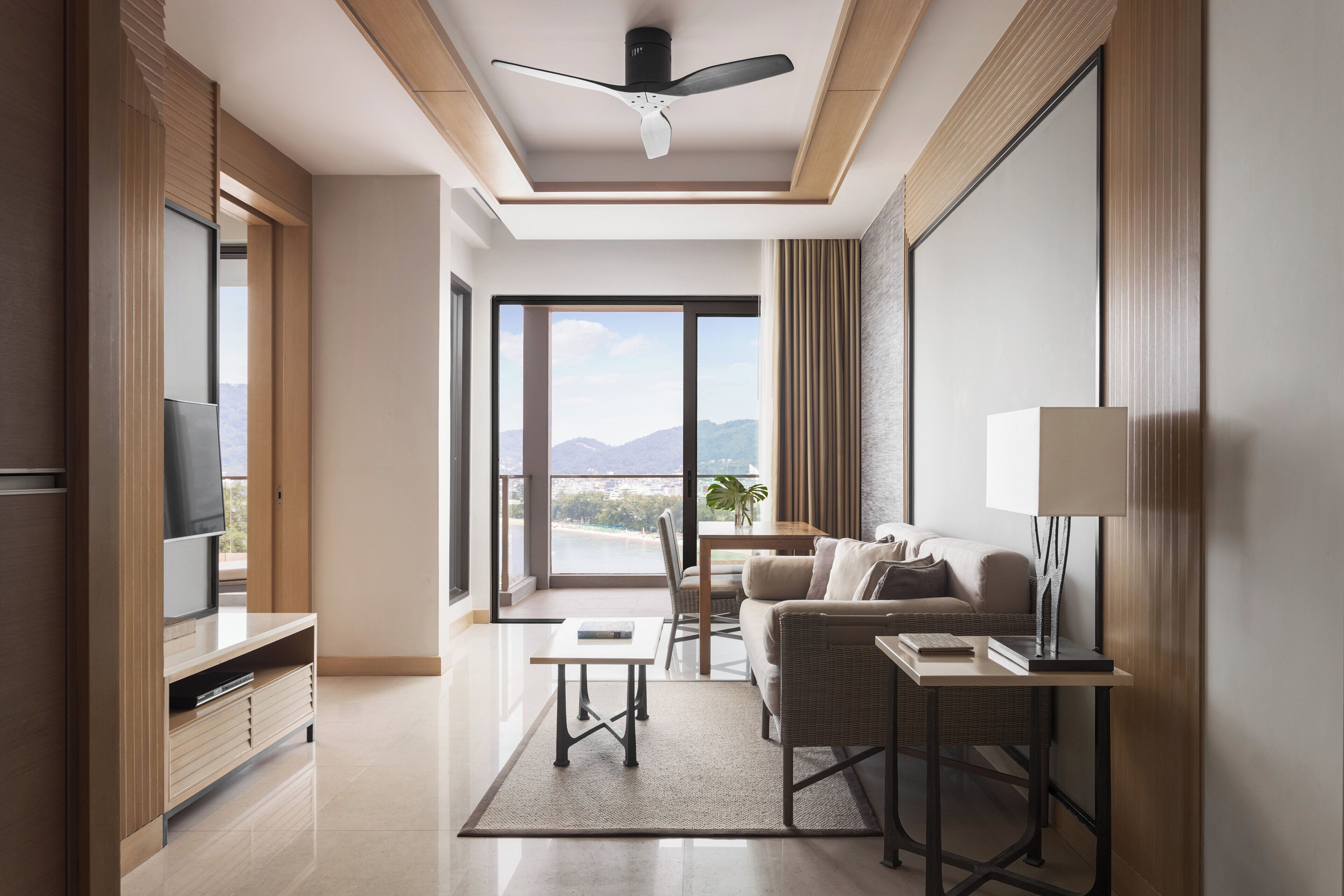 Une chambre d’hôtel moderne dotée d’une télévision à écran plat, d’un canapé, d’une table à manger et d’une grande fenêtre offrant une vue sur les montagnes.