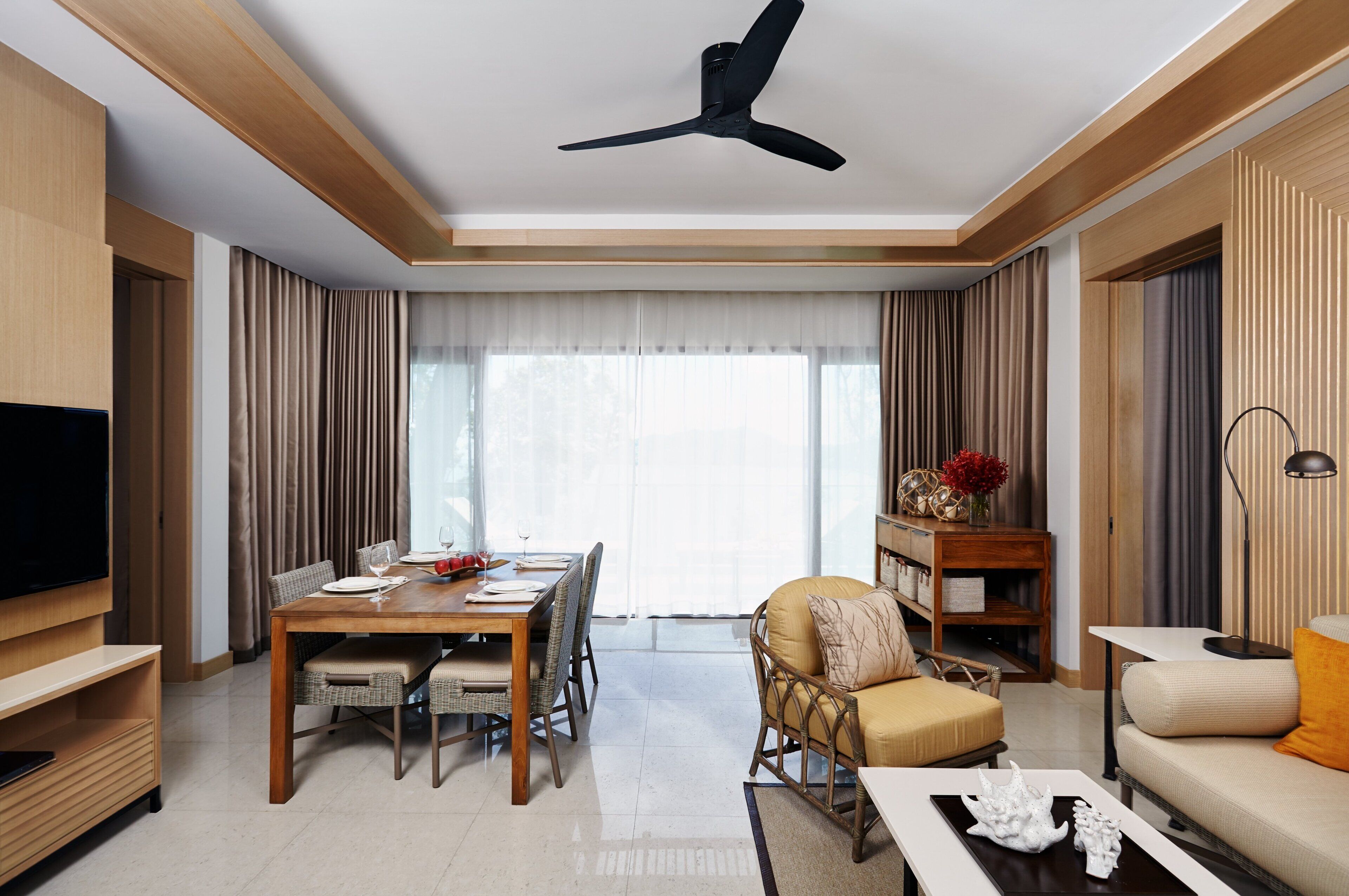 A modern living room with a dining area, a sofa, a TV, and a ceiling fan.