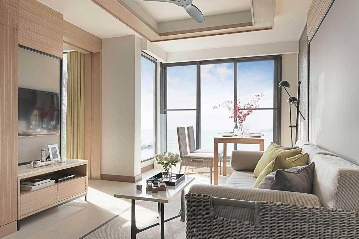Een moderne woonkamer met een bank, salontafel en televisie. Er is een balkon met een tafel en stoelen.