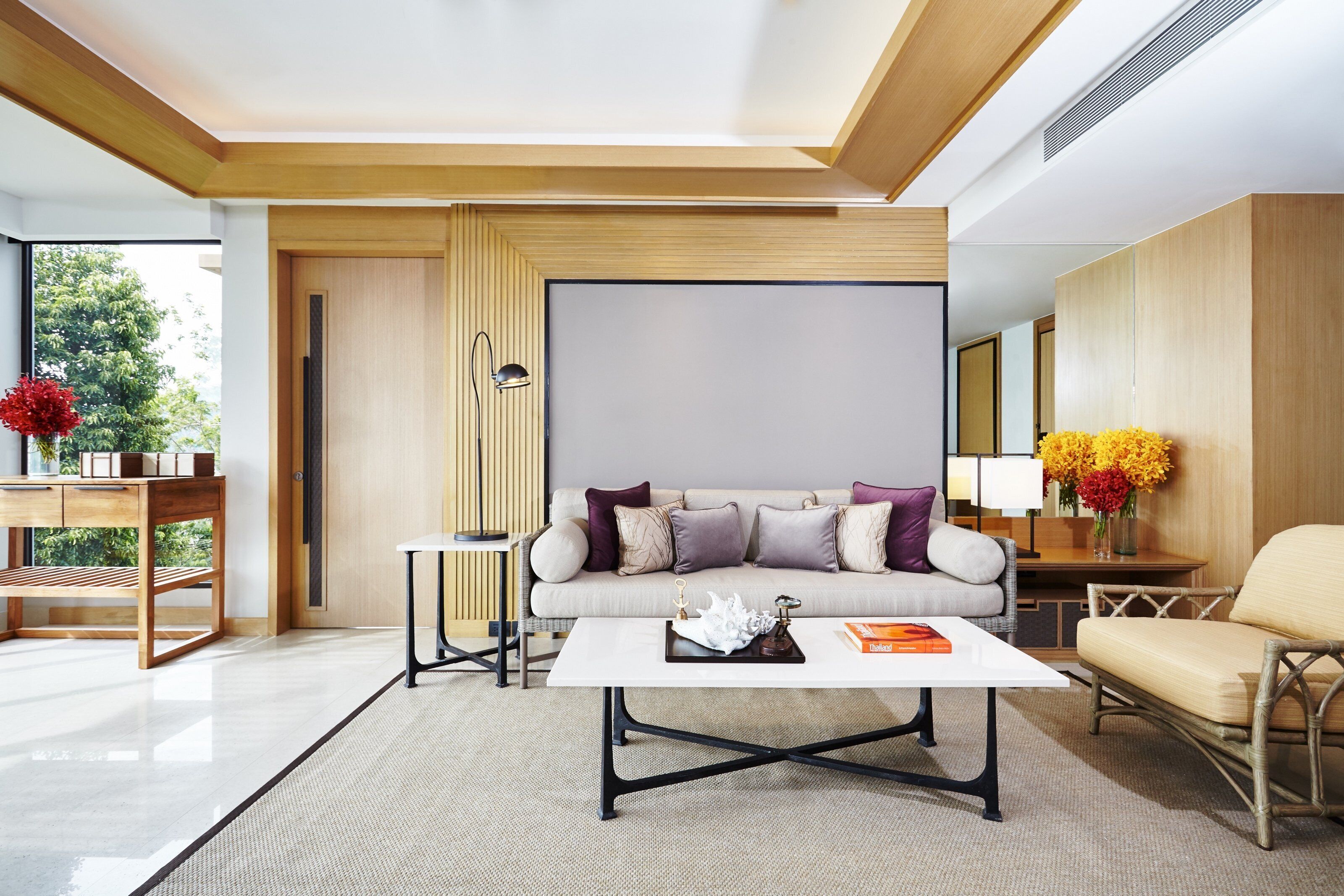 A modern living room with a sofa, coffee table, and a view of the outdoors.
