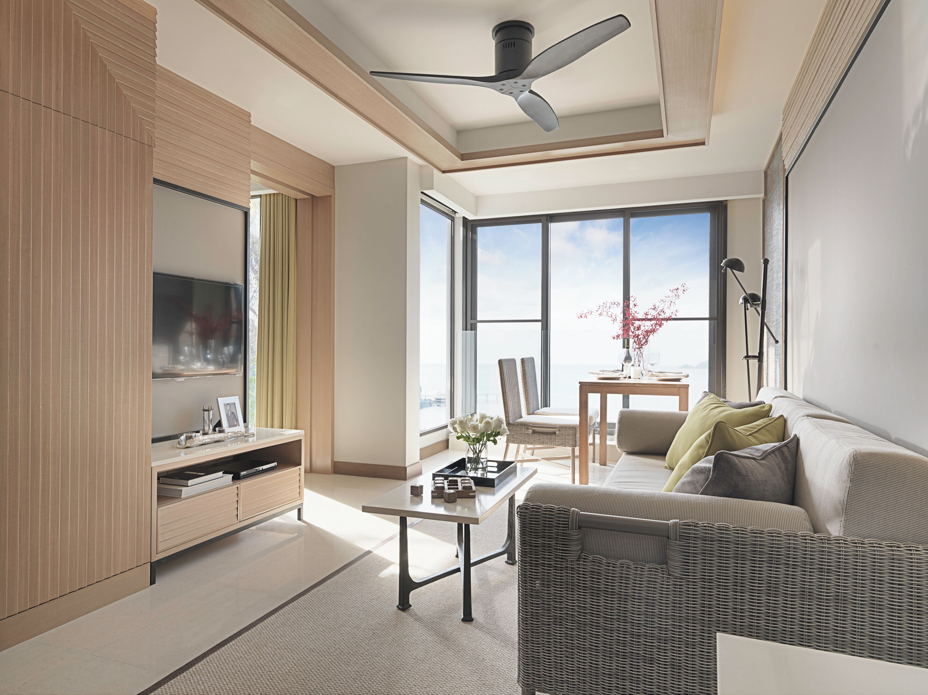A modern living room with a flat-screen TV, a dining table, and a sofa.