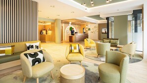 A modern lobby with a reception desk, seating area, and a large window. - Citadines Toison d'Or Brussels (Brussels)