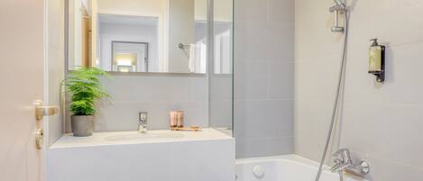 A modern bathroom with a glass shower enclosure, a white sink, and a mirror.