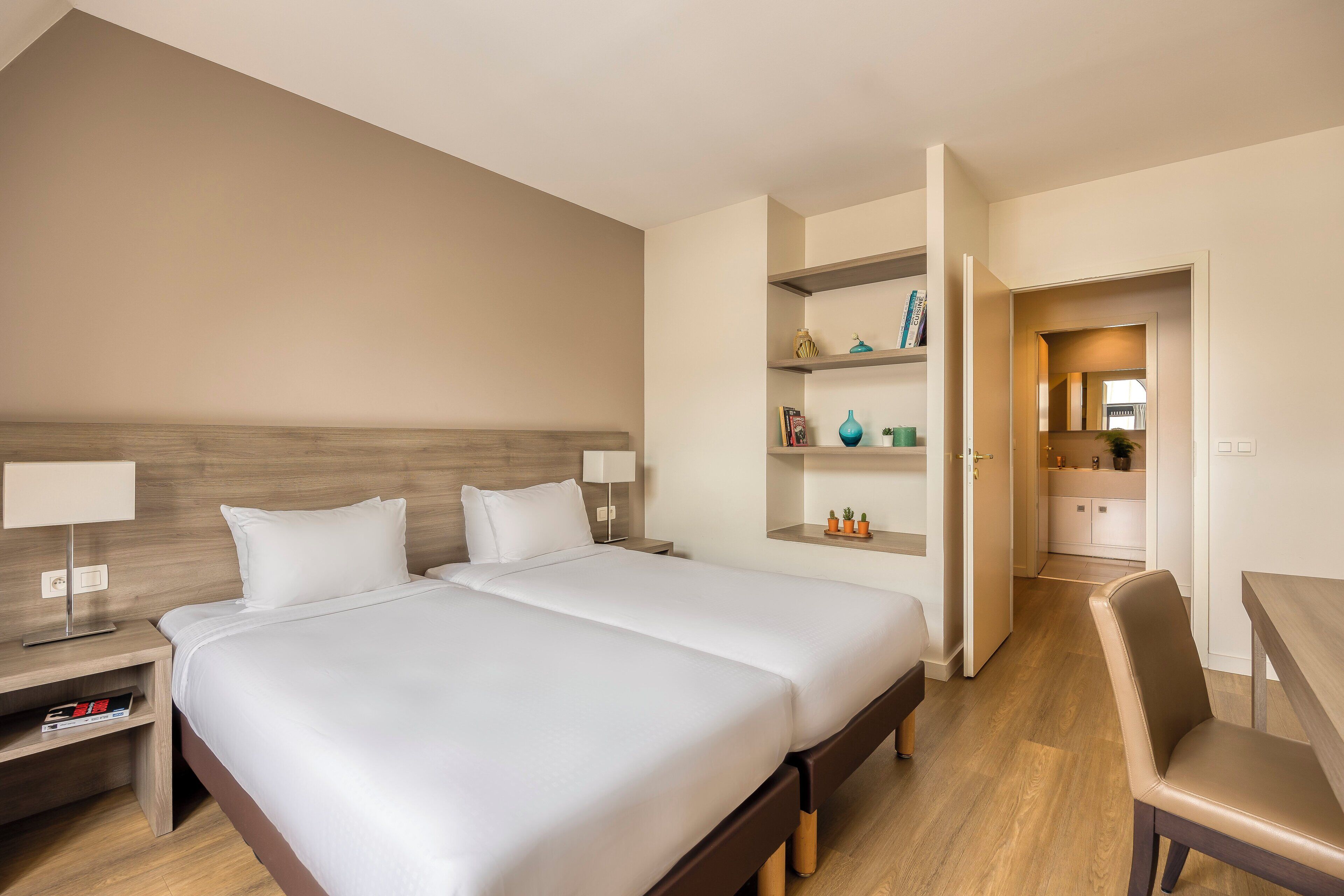 Habitación de hotel con dos camas, un escritorio y un rincón americano.