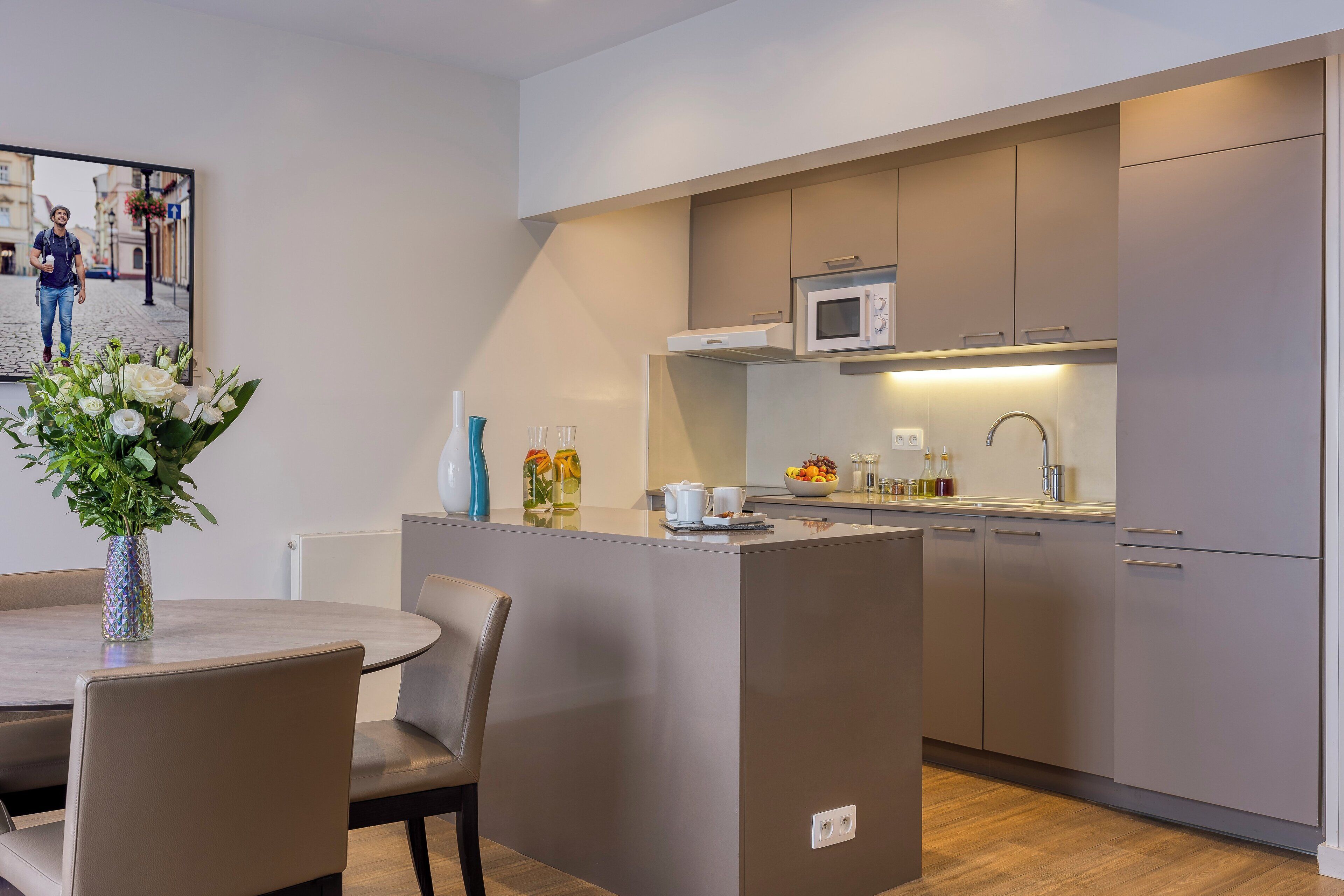 A modern kitchen with a central island, a microwave, and a sink. There is a dining area with a table and chairs.