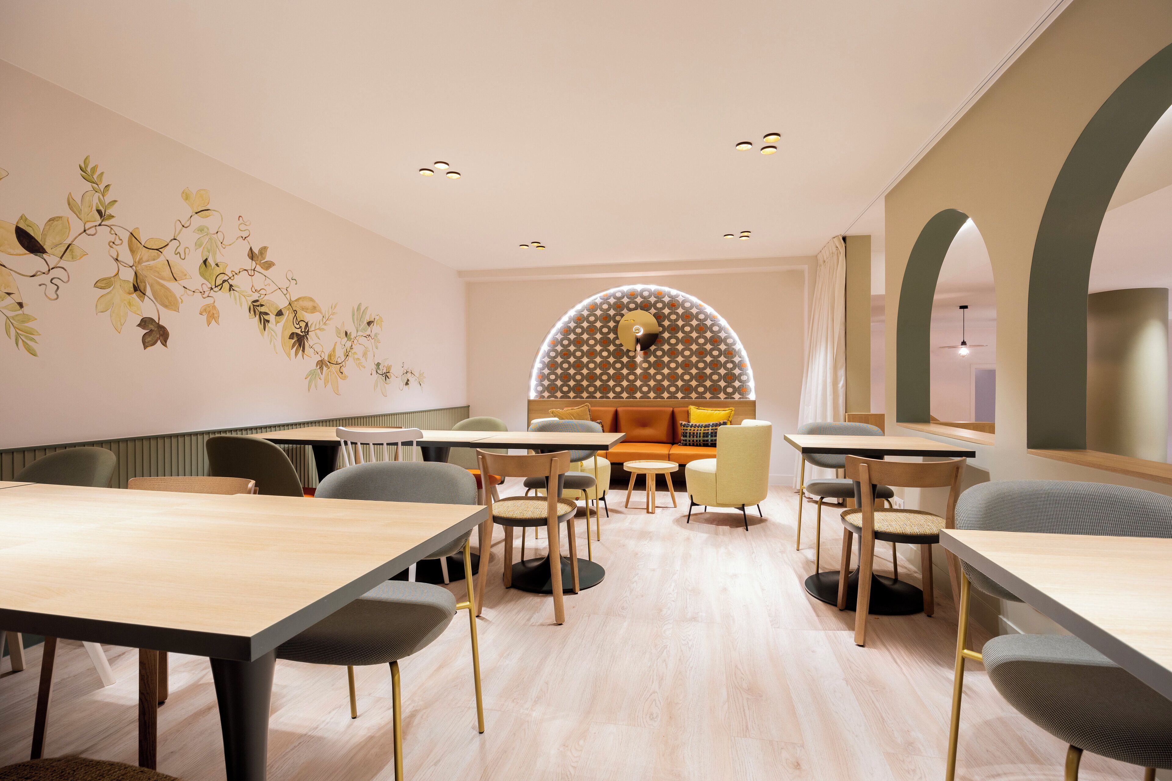 A modern conference room with a long table, several chairs, a sofa, and a decorative wall mural.