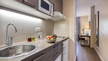 Una cocina moderna con un lavamanos de acero inoxidable, un microondas y un bol de fruta en la encimera.