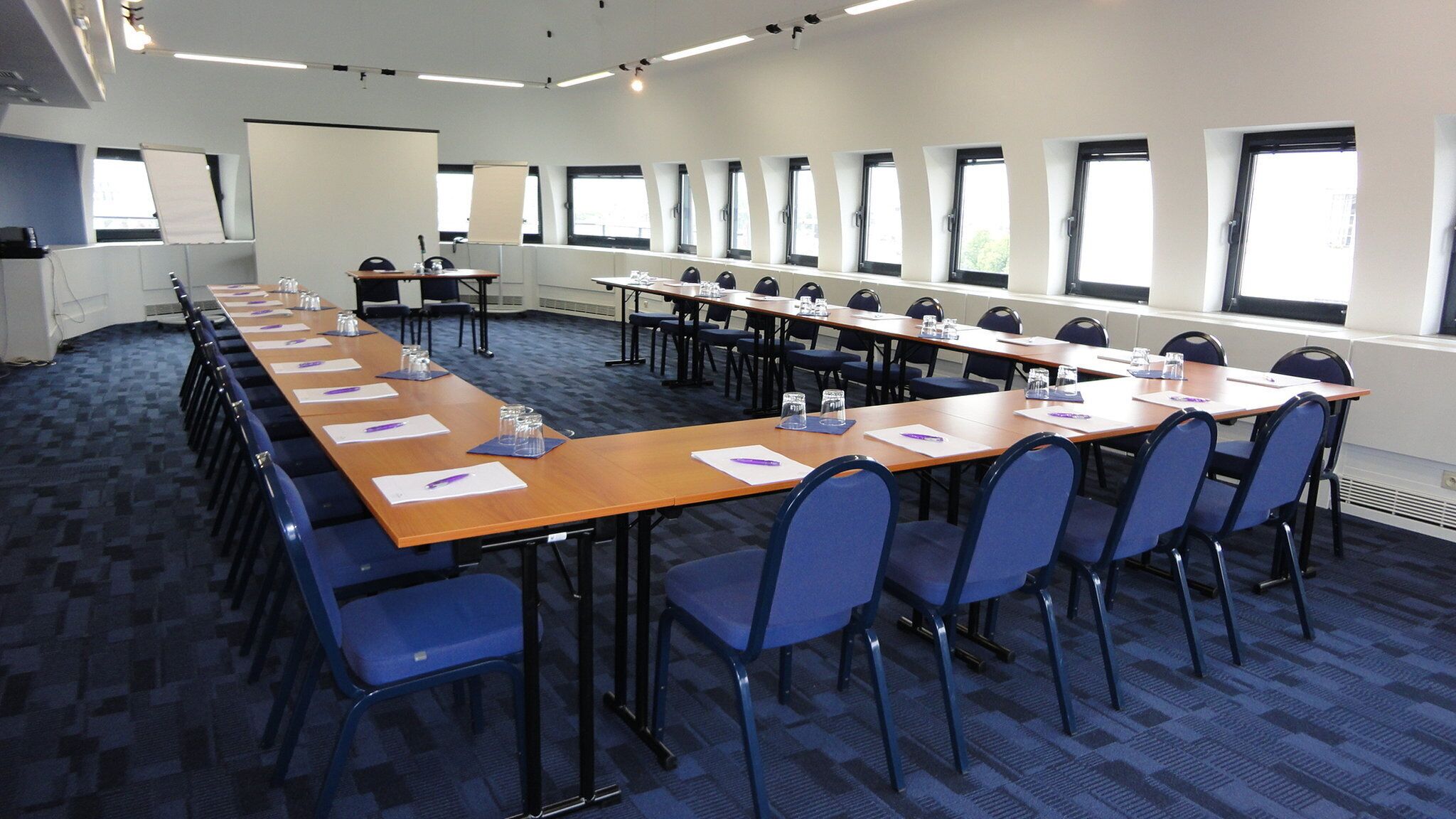 A conference room with long tables, chairs, and a whiteboard.