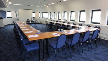 A conference room with long tables, chairs, and a whiteboard.