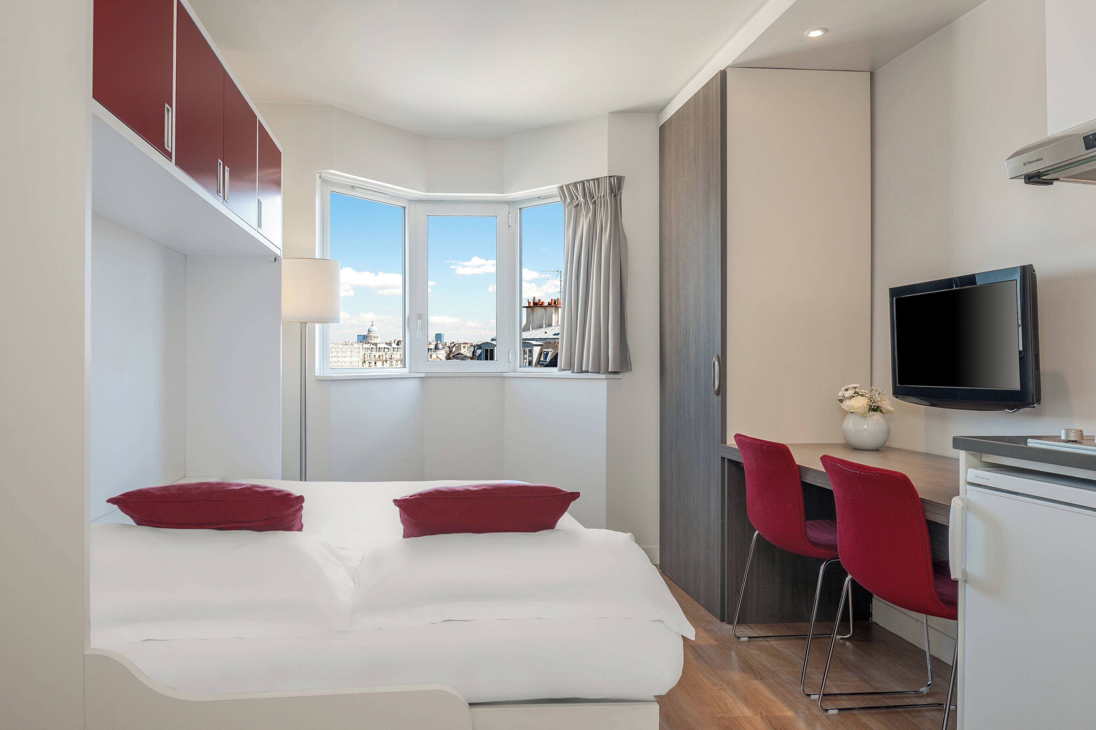 A modern hotel room with a bed, a desk, and a TV.