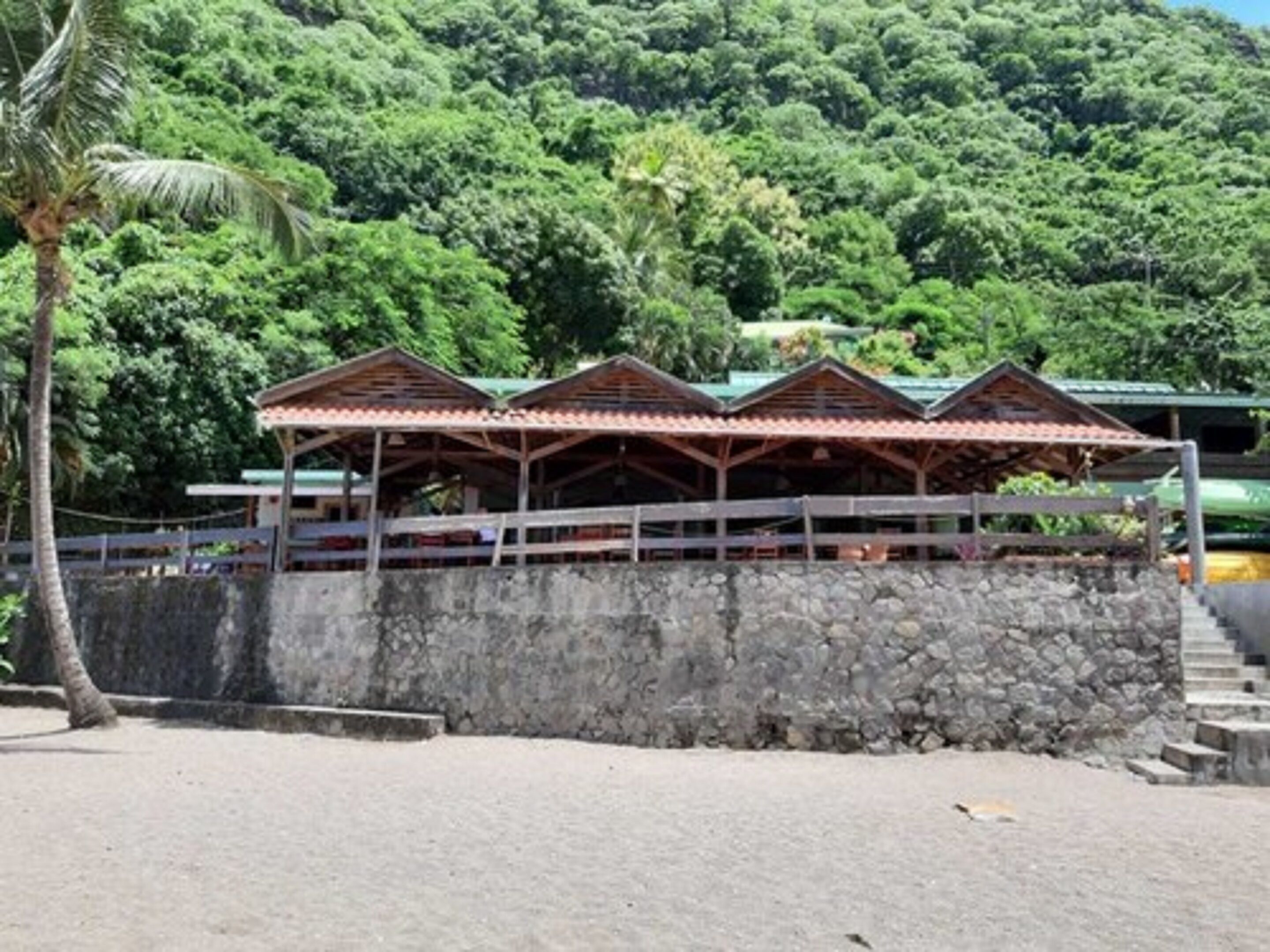 A building with a stone wall and a wooden structure with a tiled roof.