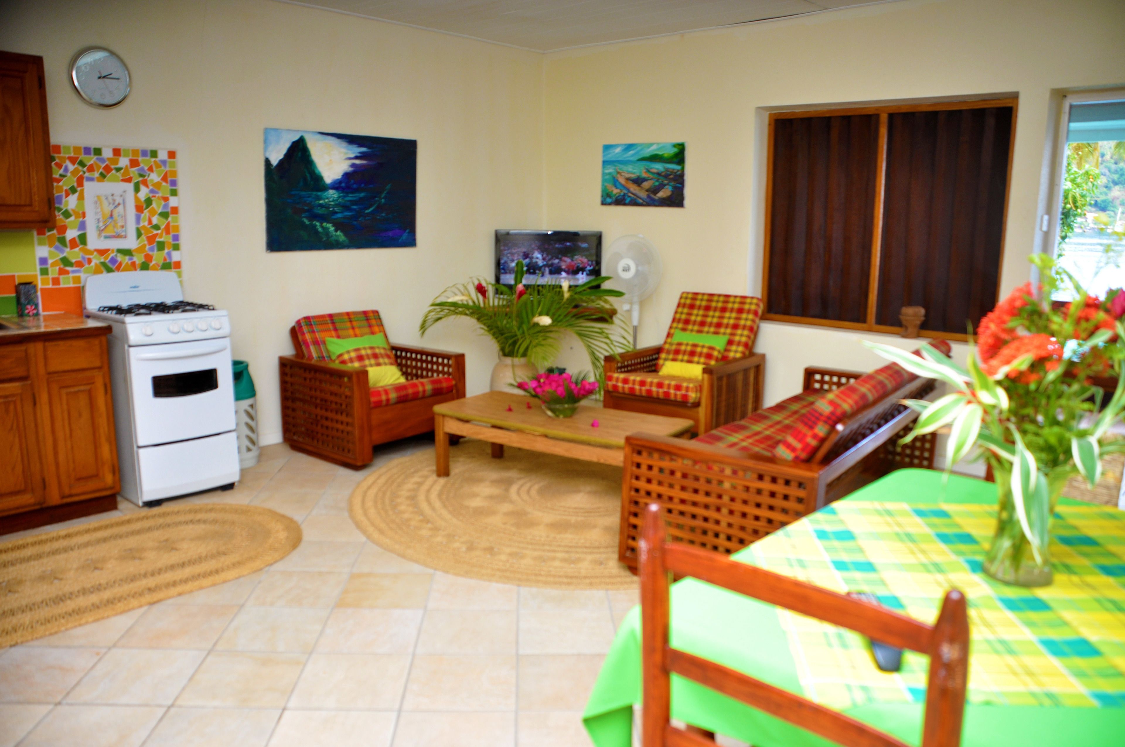 A compact living space with a kitchen area, a dining table with chairs, a sofa, and a television.