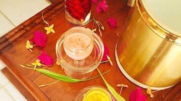 A tray with a candle, a small jar, and a golden container on a wooden surface.