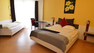 A hotel room with a large bed, a smaller bed, a desk, and a chair.