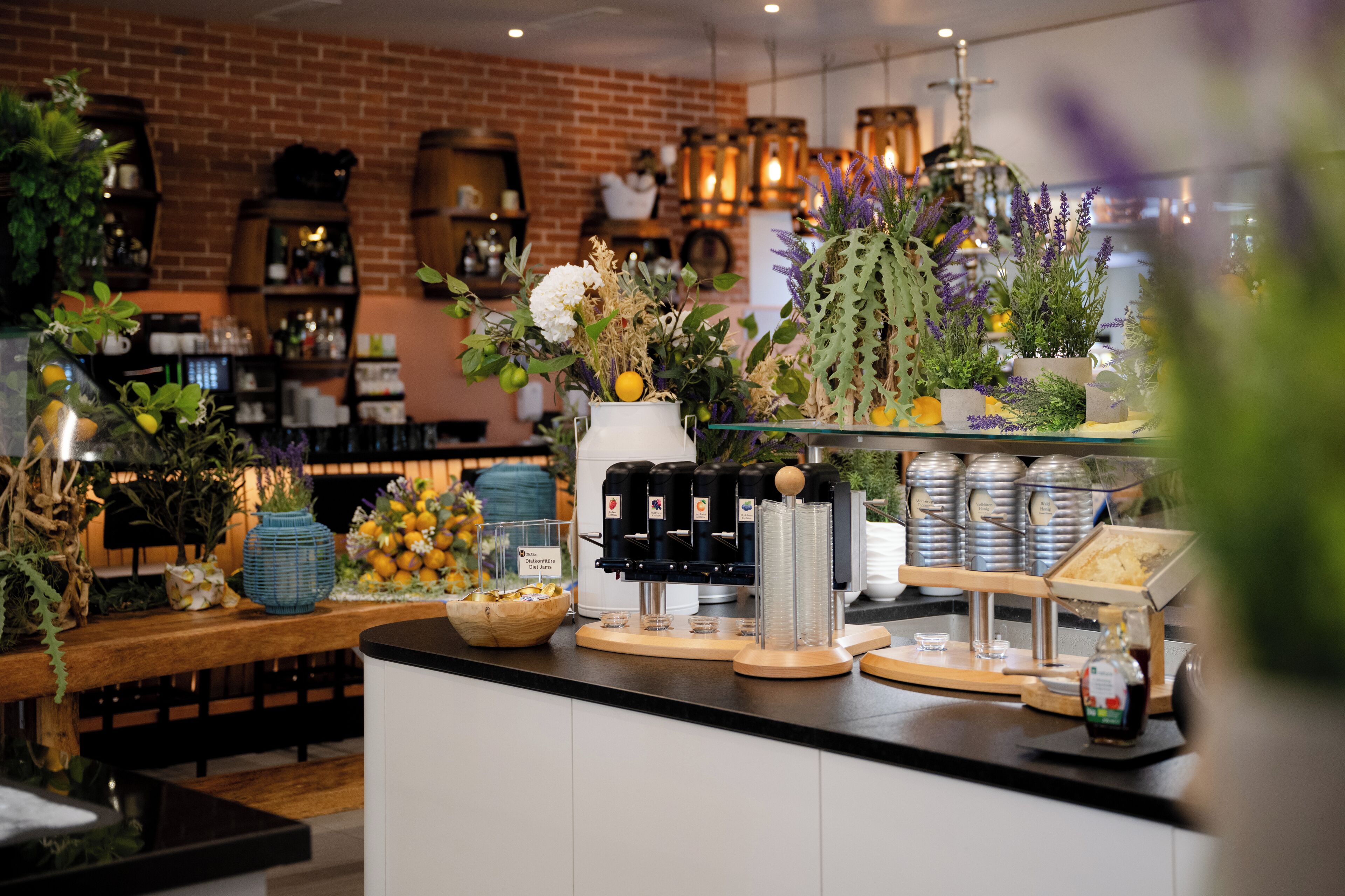 A coffee station with a coffee machine, a glass display case, and a variety of fresh flowers.