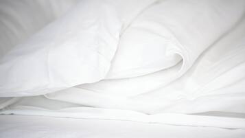 A neatly made bed with white bedding.