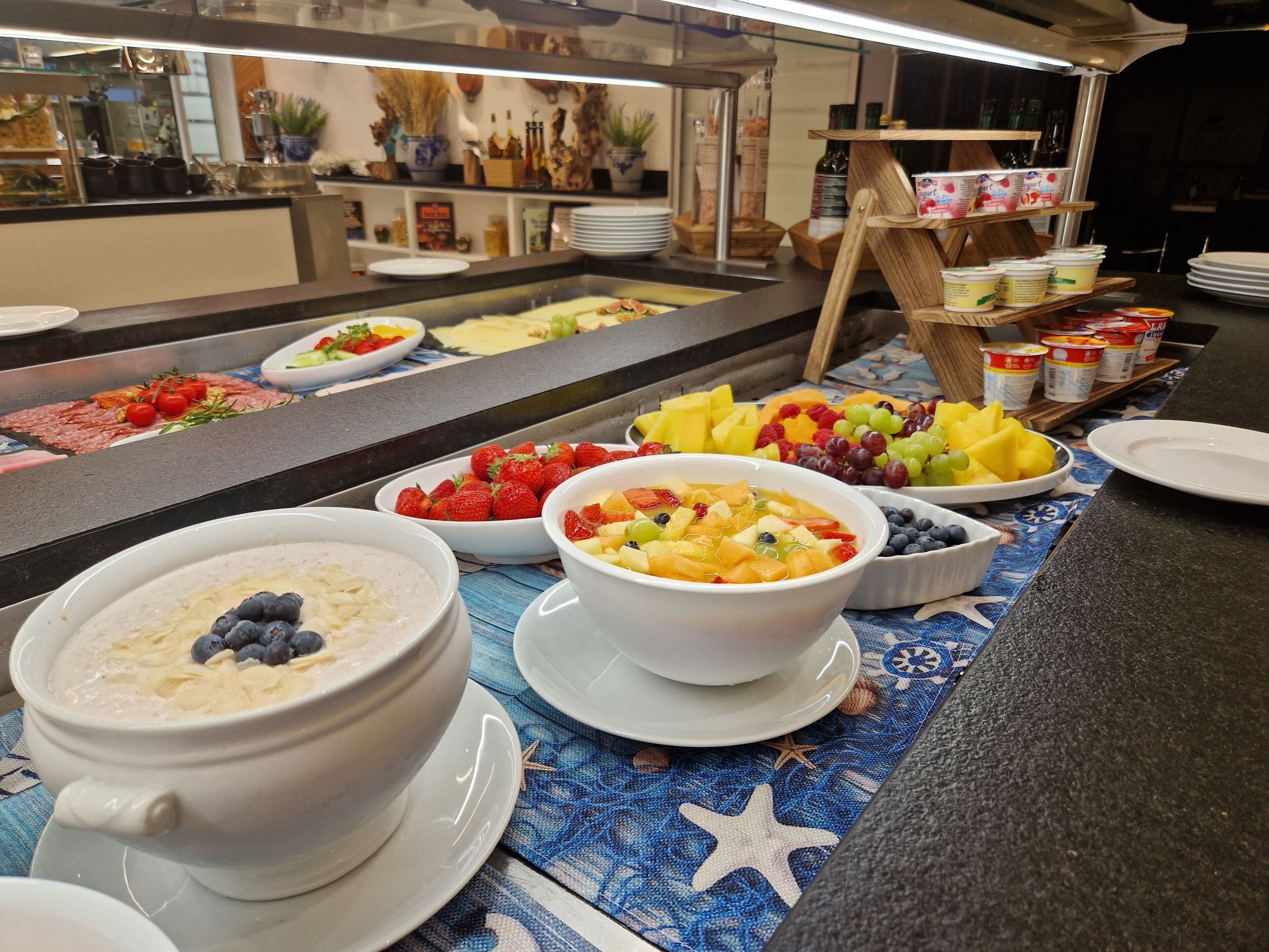Ein reichhaltiges Buffet mit verschiedenen Speisen, darunter Obst, Gemüse und Schalen Joghurt.