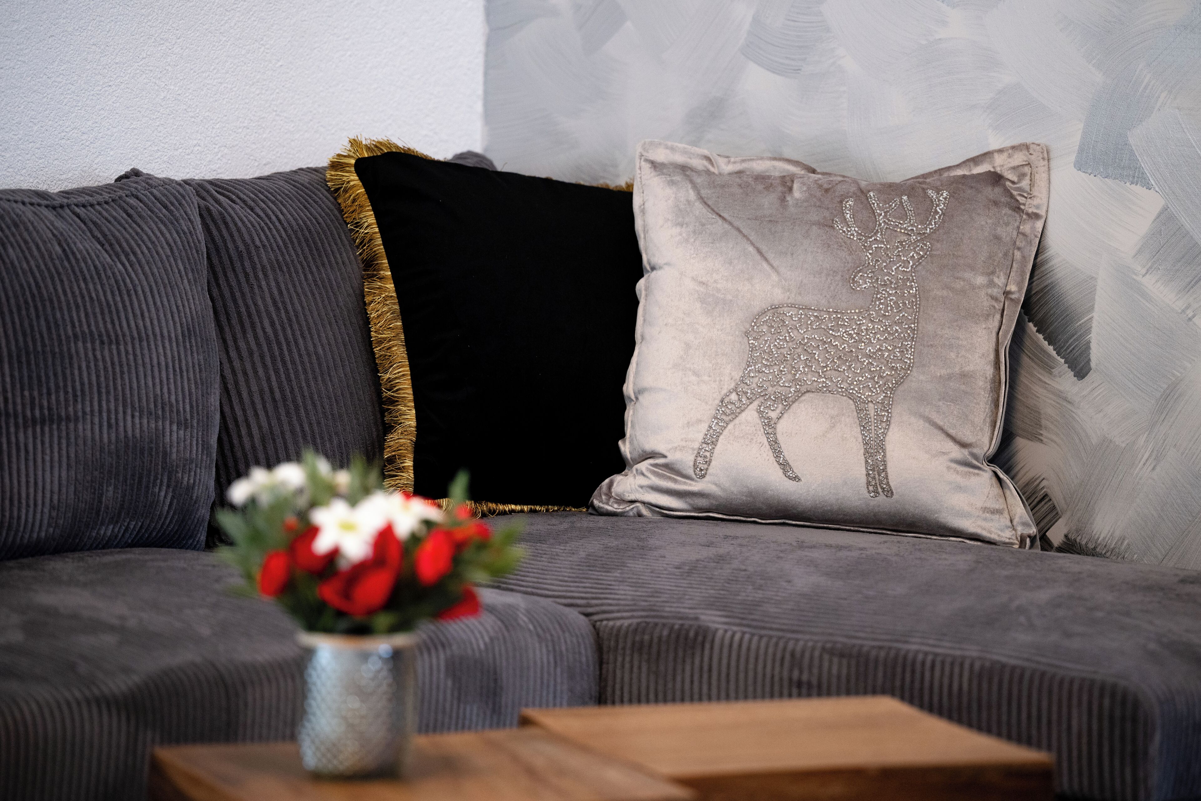 Un sofá gris con un cojín decorativo que muestra un diseño de reno.