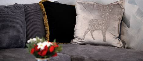 Un sofá gris con un cojín decorativo que muestra un diseño de reno.